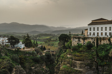 Fototapeta premium Green Tajo gorge and valley with whitewashed houses and hazy mountains in Ronda, Spain