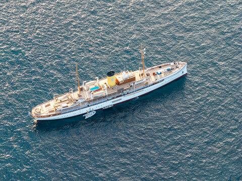 Aerial view of a luxury yacht with a yellow funnel and a swimming pool on deck sailing on the deep blue Mediterranean Sea near Cannes, Provence-Alpes-Cote d'Azur, France.