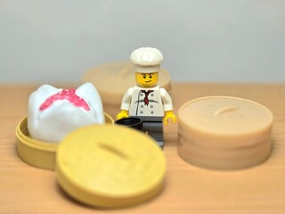 Obraz premium Indonesia - September 26, 2026 : Mini toy of action figure at table with blur background. Miniature photography concept design. Minifigure of chef character with khinkali dumpling squishy at kitchen.