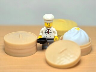 Obraz premium Indonesia - September 26, 2026 : Mini toy of action figure at table with blur background. Miniature photography concept design. Minifigure of chef character with khinkali dumpling squishy at kitchen.