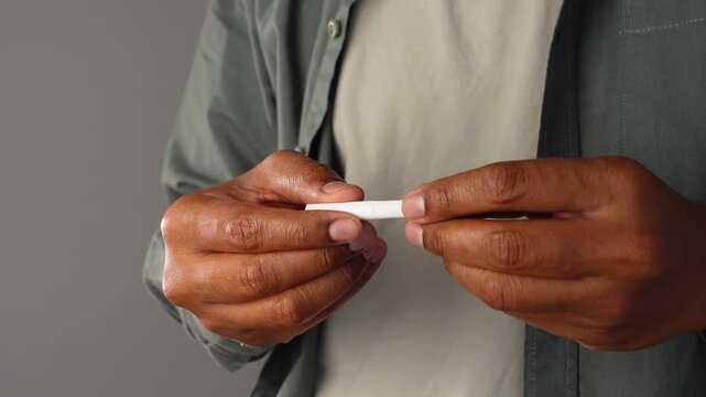 Person breaks thin white object into two pieces.