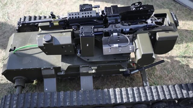 Remote weapon station with mounted machine gun installed on a tracked military robot showing unmanned combat technology and compact ground support equipment for field use today
