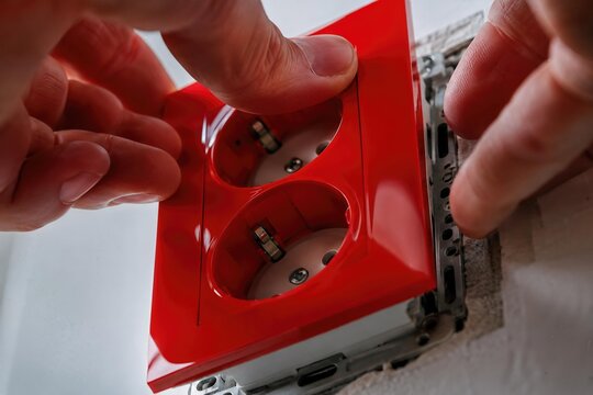Hands installing an electrical outlet cover, showing a home repair task and practical household maintenance, DIY, safety, renovation.