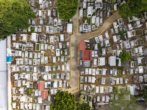 Aerial view of the Uruapan graveyard featuring numerous white stone tombs, narrow pathways, and lush green trees in Uruapan, Michoacan, Mexico.