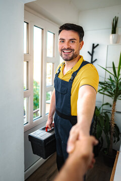 Professional handyman smiling and shaking hands with client