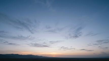 Fototapeta premium Serene sunset sky with wispy clouds over distant mountain range on the horizon