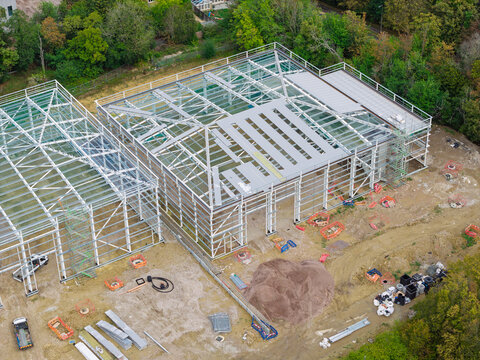 Aerial view of a data center under construction featuring a steel frame structure and partially installed roof panels surrounded by trees in the United Kingdom.