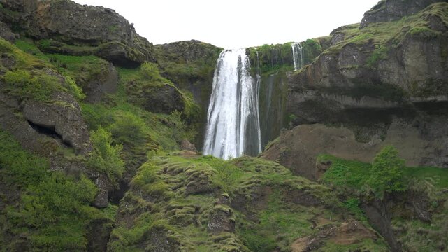 Gljufurarfoss waterfall on the Gljufura river near Gljufrabui, Iceland, falling between moss-covered rocks and green cliffs.