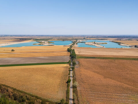 Aerial view of Szalki Kavicsbanyak gravel pit and lakes near Szalkszentmarton, Hungary, with farmland, trees and industrial extraction areas in the rural landscape.