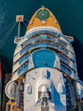 Aerial view of the Nassau Cruise Port featuring a large cruise ship with swimming pools, sun decks, and a helipad docked in the clear blue waters of Nassau, The Bahamas.