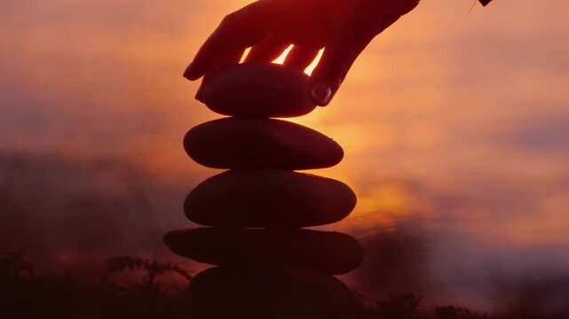 Zen stone stack balancing on beach at sunset.