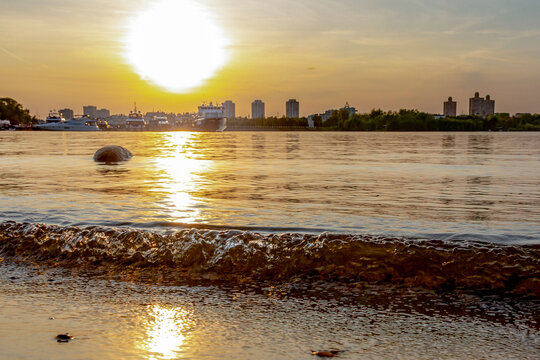 Scenic sunset view over Khimki reservoir towards Tushino with low angle perspective, small wave, evening backlight, and ships, Moscow, Russia.