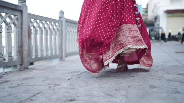 Traditional Indian woman walking forward wearing vibrant pink ethnic dress and anklet on outdoor pathway