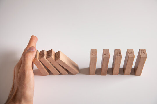 Male hand stopping wooden blocks from falling.