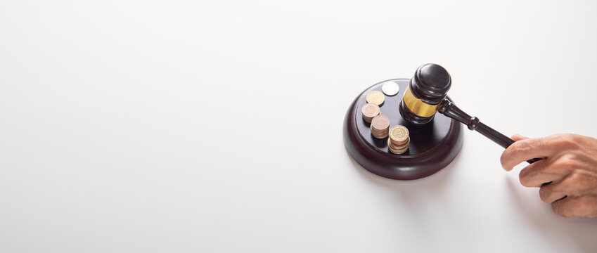 Male hand showing judge gavel over coins.