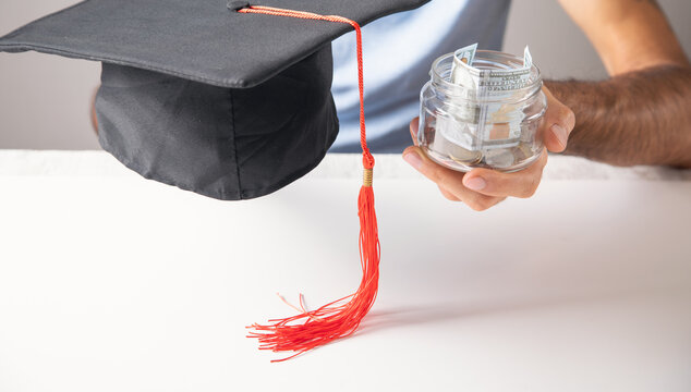 Man showing Graduation Cap with a coins.