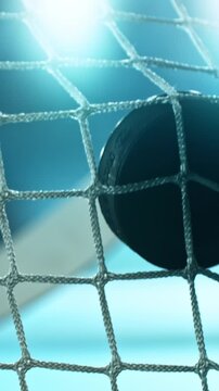 Extreme super slow motion of an ice hockey stick shooting a puck into the goal net at 1000 fps, ice particles bursting on impact with a blurred winter stadium and rink in background.