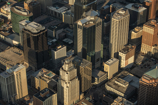 Aerial view of the dense downtown skyline featuring modern glass skyscrapers and historic buildings illuminated by the warm light of the golden hour in Kansas City, Missouri, United States.