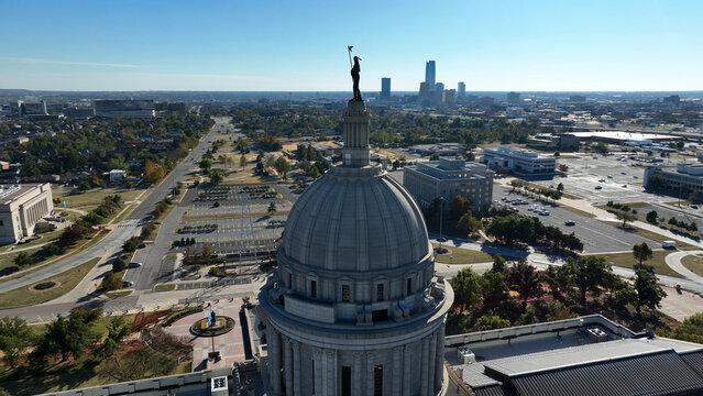 Aerial view of the Oklahoma State Capitol dome with the city skyline in the background, surrounded by parking lots and urban infrastructure in Oklahoma City, Oklahoma, United States.