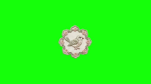 Embroidered bird patch with scalloped lace edge isolated on bright green chroma key background