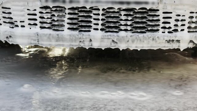 Close up video frame of an automatic underbody car wash system spraying high-pressure water jets onto a vehicle chassis. Stream of water effectively removing winter salt, mud, and dirt from the bottom