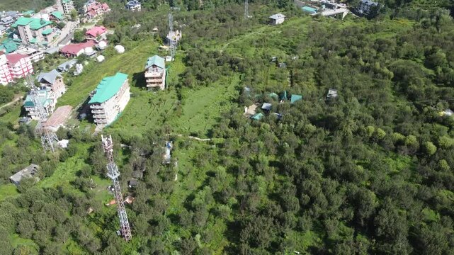 Aerial View of a Serene Village Nestled Among Lush Greenery in the Himalayas with Vibrant Yellow Tarp and Towering Trees on Sunny Day