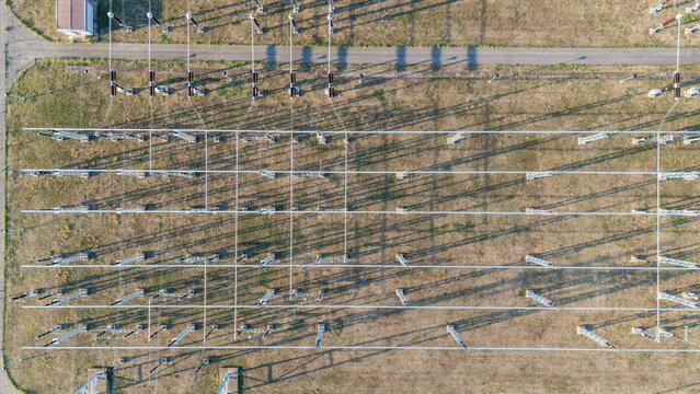 Aerial view of an electrical substation with power lines, transformers, and long shadows cast on the grassy ground in Sremska Mitrovica, Vojvodina, Serbia.