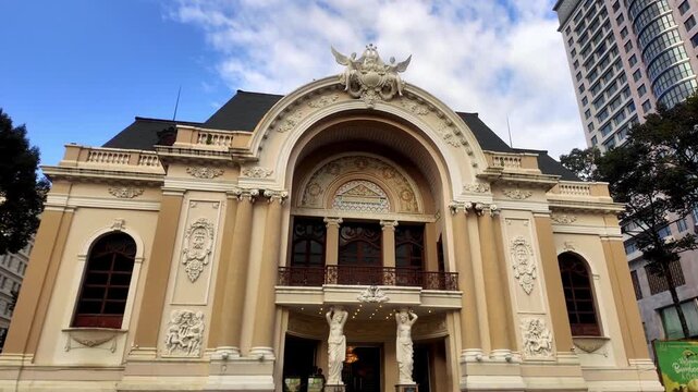 Smooth low angle tracking shot of the historic Saigon Opera House facade in Ho Chi Minh City Vietnam under bright sunny skies