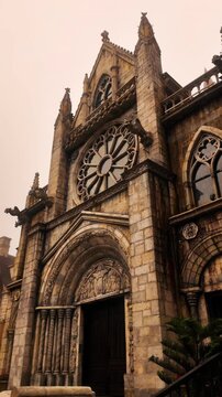 Low angle tilt shot of the Gothic cathedral facade in French Village at Ba Na Hills on a misty day, Da Nang, Vietnam