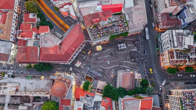 Aerial view of Monastiraki Square with its distinctive wavy paving patterns, surrounded by historic buildings with red rooftops and bustling streets in Athens, Greece.