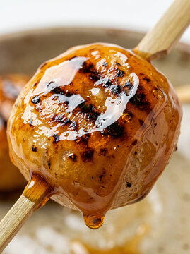 Close up of a delicious grilled dango dumpling with sweet soy glaze on a wooden skewer.