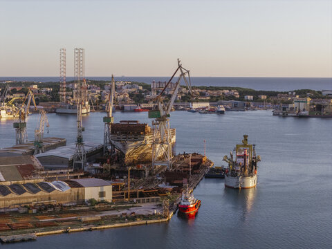 Aerial view of the Uljanik Shipyard in Pula, featuring large industrial cranes, a ship under construction in the dry dock, and port facilities in Pula, Istarska zupanija, Croatia.