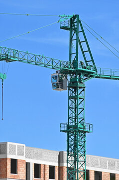 Green tower crane and house from red brick