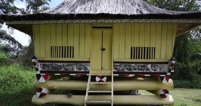 A traditional wooden stilt house built without nails serves as an authentic architectural representation of the dwelling for a royal commander's family within the Simalungun Kingdom compound.