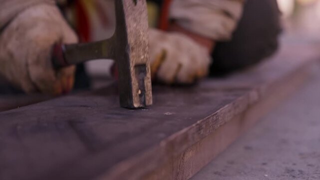 Worker hammering nail into wooden formwork board