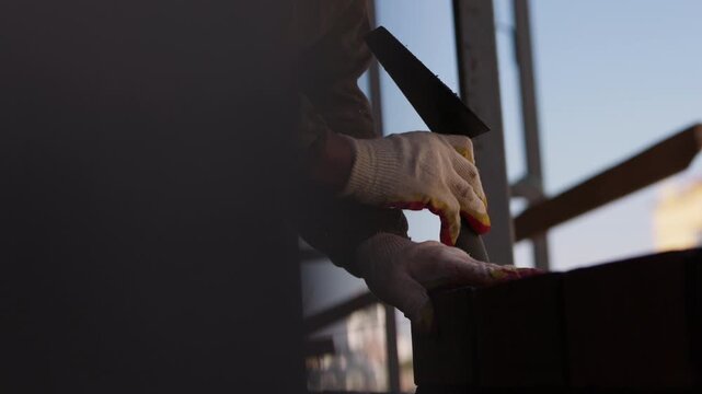 Worker positioning laid brick for precise masonry wall alignment
