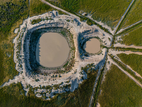 Aerial view of two circular ponds surrounded by arid earth and green fields in the flat landscape of Hay, New South Wales, Australia.