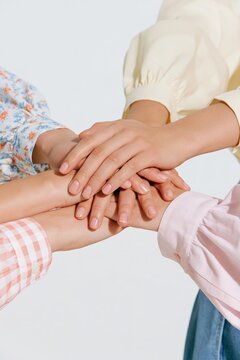 Diverse group of women stacking hands together as a symbol of teamwork, unity, friendship and mutual support