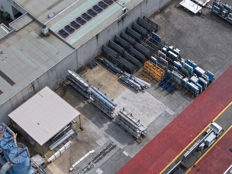 Aerial view of industrial site with rows of stored metal components, factory buildings with solar panels on the roof, and a loading area with a truck, Melbourne, VIC, Australia.