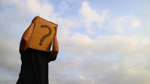 Person holding a cardboard box with a question mark over their head against a cloudy sky.