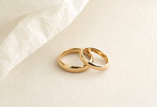 Two gold wedding rings placed on light fabric surface