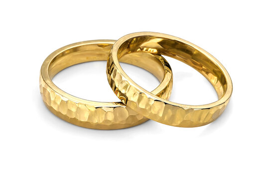 Two golden wedding rings with hammered texture design on white surface