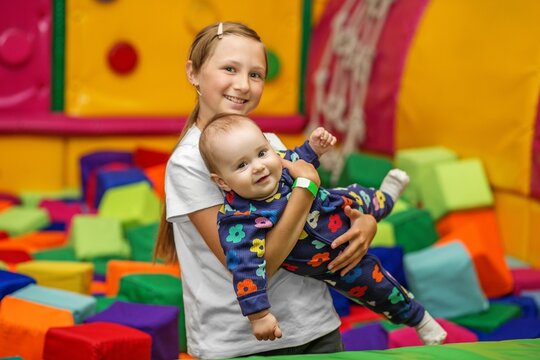 Older sister playing with baby girl in indoor soft play area