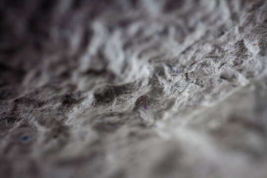Extreme close up of old gray handmade paper clay with a structure and rough texture. Paper recycling. Selective soft focus, shallow depth of field.