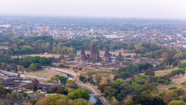 Aerial view of Prambanan Temple surrounded by lush greenery, ancient stone structures, and a winding river in Kecamatan Prambanan, Daerah Istimewa Yogya, Indonesia.