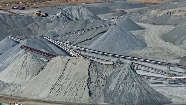 Aerial view of a large industrial quarry featuring massive piles of crushed stone and gravel with complex conveyor belt systems for material processing in Golden, Colorado, United States.