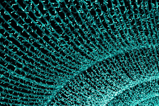 Christmas street illumination bokeh, garland with turquoise lights arranged in dense flowing patterns, shining arch glowing on dark background, festive sparkling texture with modern winter atmosphere