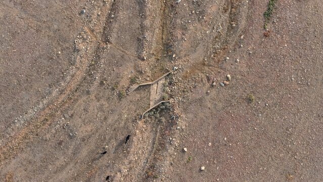 Aerial view of a small concrete drainage structure set within a dry, rocky desert landscape with sparse vegetation and scattered dark rocks in Golden, Colorado, United States.