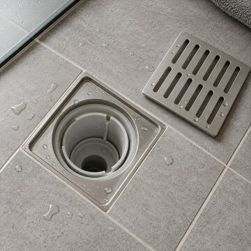 Open bathroom floor drain with its metal cover removed