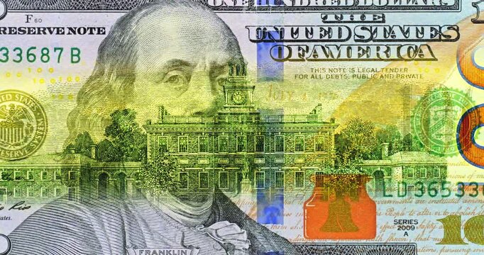 100 dollar bill under moving security scan. Benjamin Franklin portrait anchors colorful United States banknote artwork. Engraved details and national emblems form striking historic design.